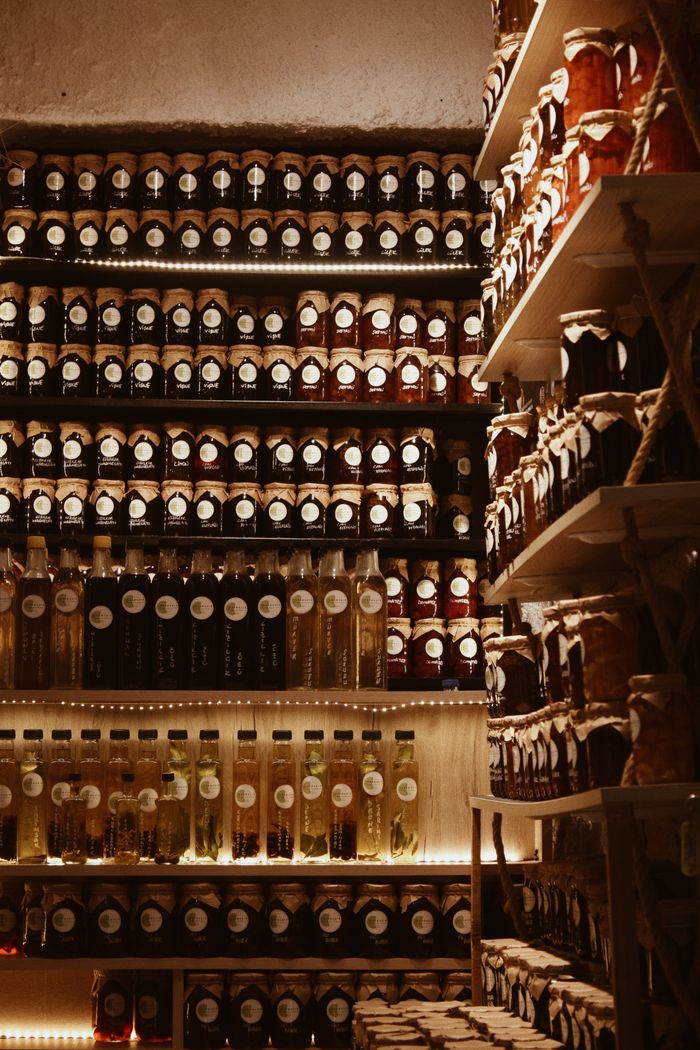 A warm, rustic indoor display of artisanal jars and bottles arranged on shelves.