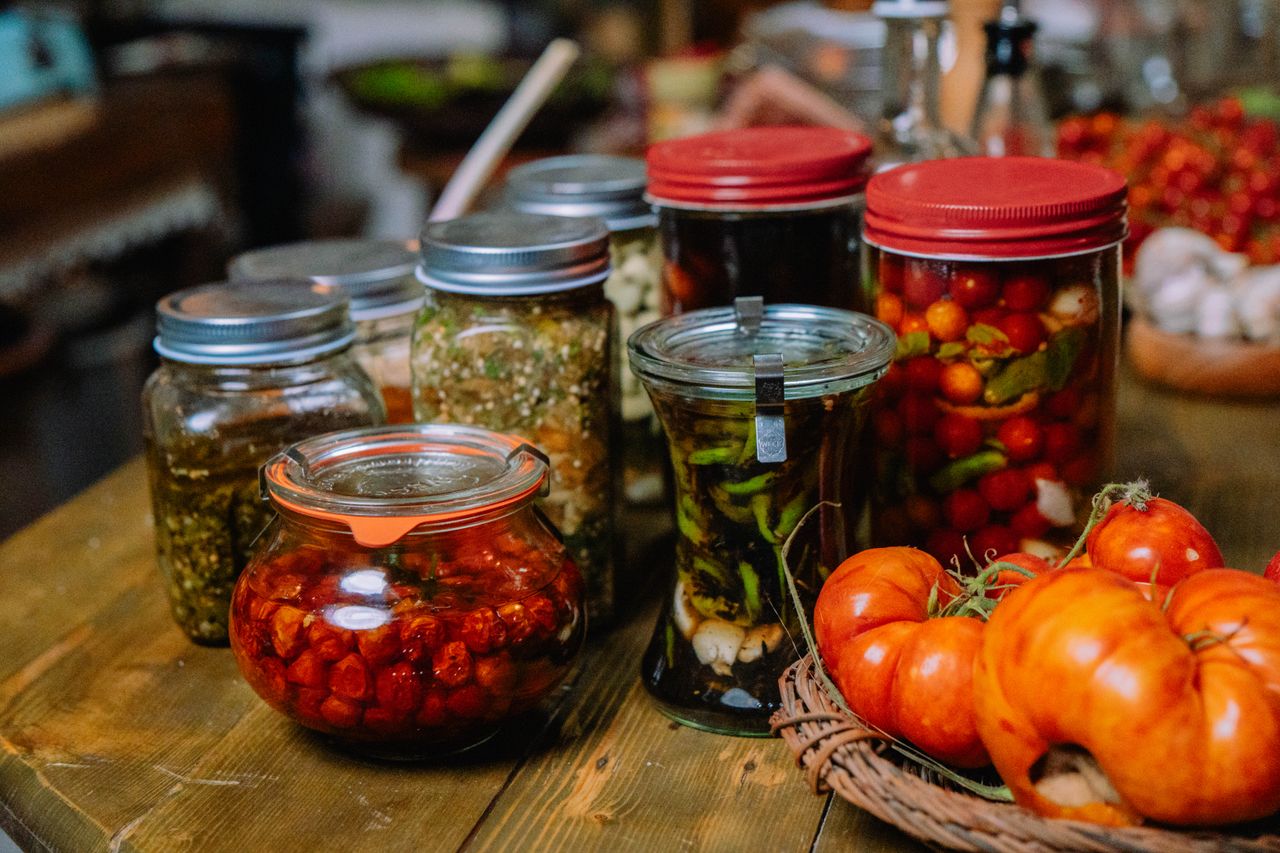 Colorful jars of homemade preserved vegetables and pickles on a rustic wooden table.